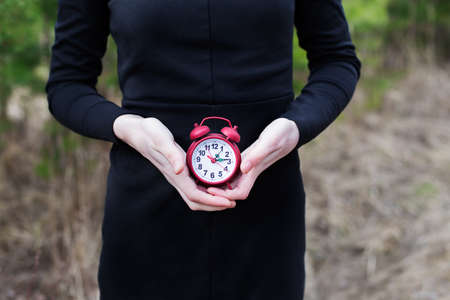 Women in black dress holding red alarm clockの写真素材