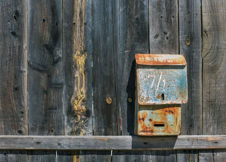 Old shabby mailbox on fenceの写真素材