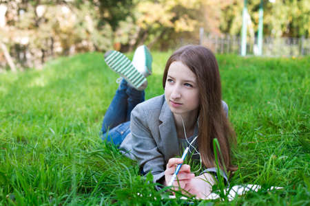 Student with headphones lying on grass and looking awayの写真素材