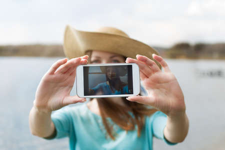 Girl in hat taking her photo on the phone