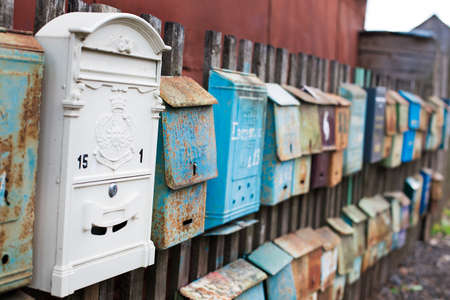 Set of old mailboxes with rust attached to the fenceの写真素材