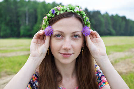 Freckled girl holding two field flowers at eye level