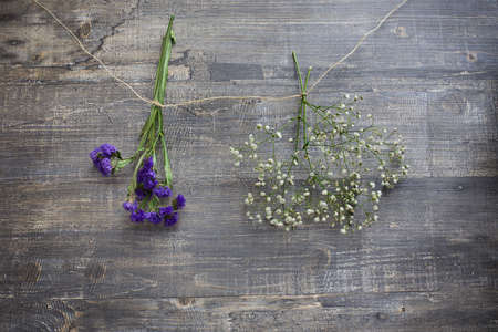 Two flower bunches hanging on string on wooden backgroundの写真素材