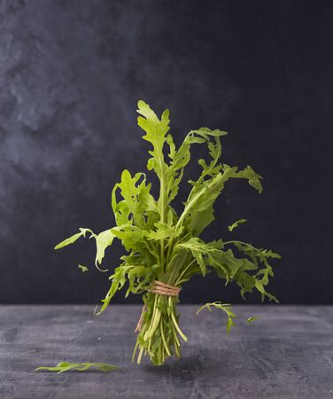 Fresh raw green arugula falling in the air over dark concreate backroundの写真素材