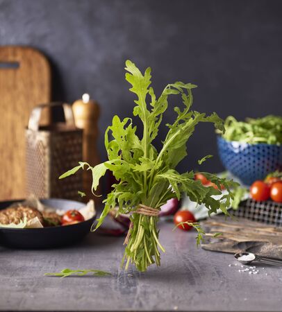 Fresh raw green arugula falling in the air  on kitchen table over dark concreate backgroundの写真素材