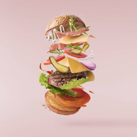 Delicious burger with flying ingredients isolated on pink backgroundの写真素材