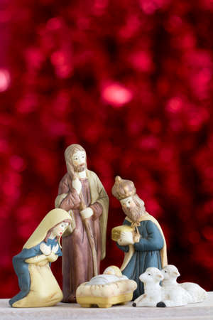 Nativity Scene with Baby Jesus, Mary, Joseph, Sheep and a Wise Man on a Red Background with Copy...