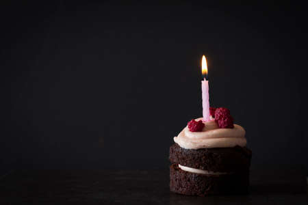 Chocolate Birthday Cupcake with Raspberries and Candle on Dark Background with Copy Space Horizontalの写真素材