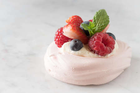 Close Up of a Meringue Decorated with Cream, Strawberry, Raspberry, Blueberry and Mint on a Light...