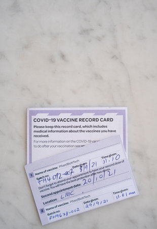 AUCKLAND, NZ - OCT 14 2021: Two New Zealand COVID-19 Vaccination Record Cards on Table Oct 14 2021のeditorial素材