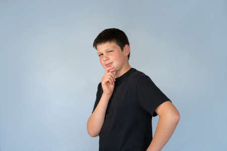 Fun Portrait of Teenage Boy with cheeky thoughtful week on Face Blue background with Copy Spaceの写真素材