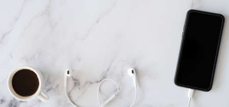 Flat Lay Banner of Mobile Phone, Headphones, and Coffee on a Table with Copy Spaceの写真素材