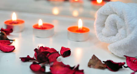 Spa atmosphere with petals, towel and light candles.の写真素材