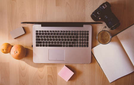 Simple but creative workspace: laptop in focus and coffee, business cards, tablet and phone in...