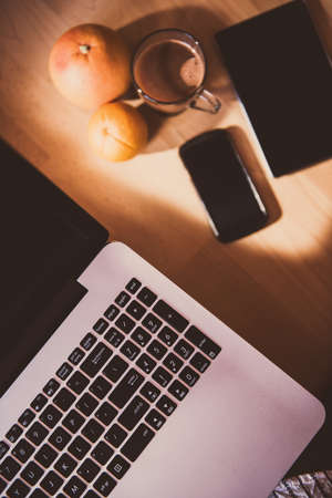 Simple but creative workspace: laptop in focus and coffee, business cards, tablet and phone in background.の写真素材