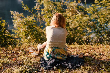 Girl sitting and thing in a park - back view.の写真素材