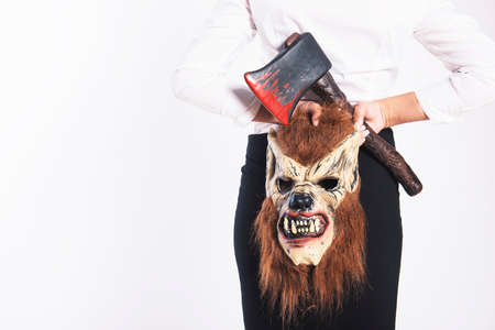 Girl with a wolf mask and a bloody axe in business clothingの写真素材
