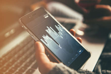 Girl with a smart phone analyzing market exchange rates.の写真素材