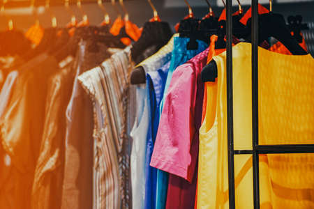 Colorful clothes on hangers in a luxury fashion store with backlight effect.の写真素材