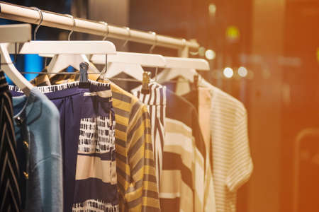 Fancy clothing hanging on racks in a storeの写真素材