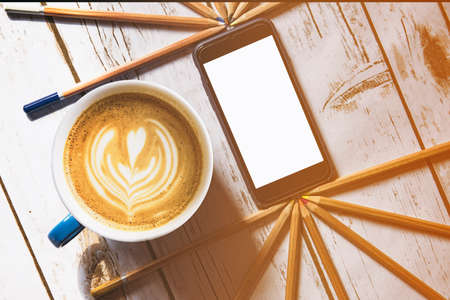 Creative break  - flat white coffee and a smart phone with copy space on a wooden table background.