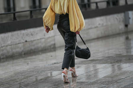 Paris, France â March 2, 2020: Woman wearing black leather trousers, yellow bouffant blouse, white high heel sandals and a black Prada handbag - streetstylefw20のeditorial素材