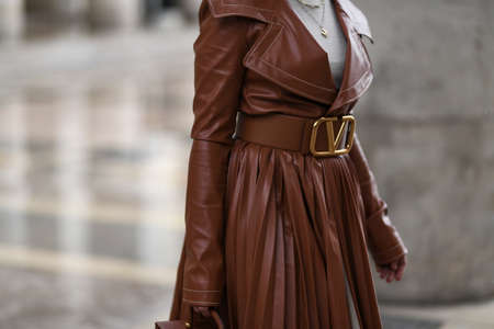 Paris, France - February 29, 2020: Woman wearing a brown leather pleated trench coat detail - streetstylefw20のeditorial素材