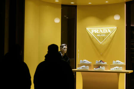Milan, Italy - January 11, 2020: People in front of a Prada sneakers showcase at night