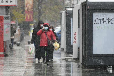 Bucharest, Romania - November 30, 2020: People wearing protective masks walk through the snow during coronavirus outbreak.のeditorial素材