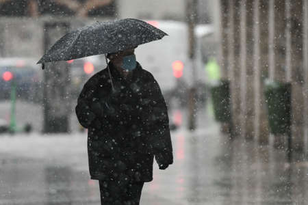 Bucharest, Romania - November 30, 2020: People wearing protective masks walk through the snow during coronavirus outbreak.のeditorial素材