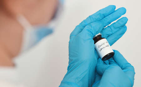 Female doctor holding in her hand coronavirus vaccine - covid-19 health conceptの写真素材