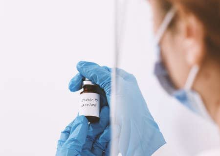 Female doctor holding in her hand coronavirus vaccine - covid-19 health concept