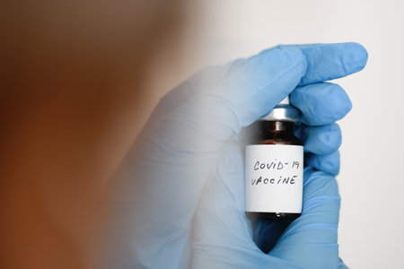 Female doctor holding in her hand coronavirus vaccineの写真素材