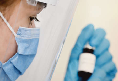 Female doctor holding in her hand coronavirus vaccine - covid-19 health concept