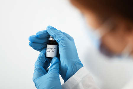 Female doctor holding in her hand coronavirus vaccine - covid-19 health concept