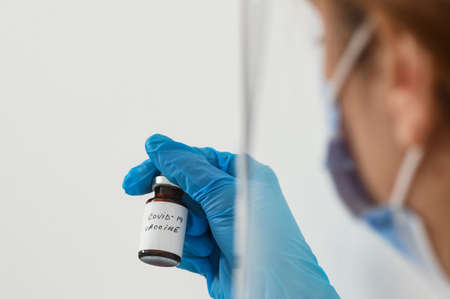Female doctor holding in her hand coronavirus vaccine - covid-19 health concept