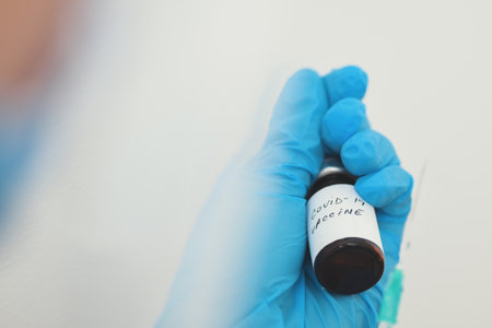 Coronavirus vaccine in glass bottle in hand of a doctorの写真素材
