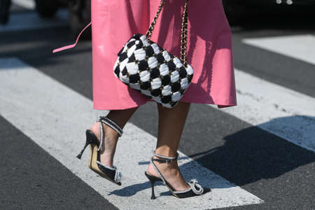 Milan, Italy - September 24, 2021:  Street style outfit, fashionable woman wearinga pink long coat, a black and white checkered handbag from Chanel, black pumps heels shoes with silver knotted rhinestones on the streets of Milan, Italy.のeditorial素材