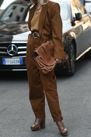 Milan, Italy - September 22, 2021:  Street style outfit, fashionable woman wearing a beige t-shirt, a brown blazer, large suit pants and a brown shiny leather handbag on the streets of Milan, Italy.のeditorial素材