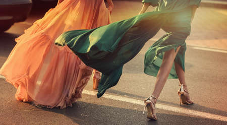 Women wearing elegant dresses, street style detail.