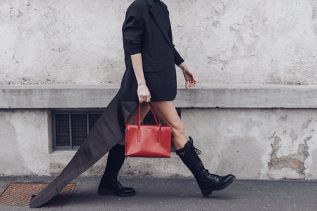 MILAN, ITALY - FEBRUARY 24, 2022: Street style outfit: girls wearing red bag and black shoes by Prada.のeditorial素材