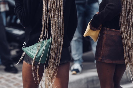 MILAN, ITALY - FEBRUARY 24: Street style outfit - girls wearing Prada purses and shoes.
