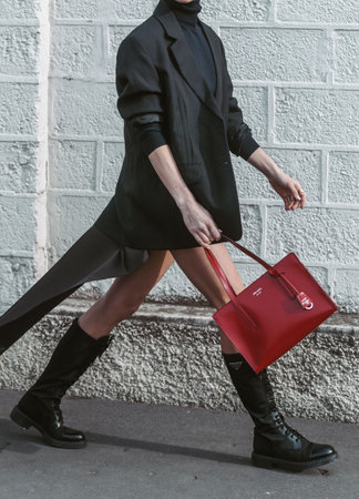 MILAN, ITALY - FEBRUARY 24, 2022: Street style outfit: girls wearing red bag and black shoes by Prada.のeditorial素材