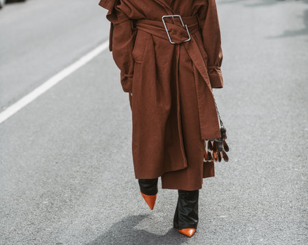 Milan, Italy - February, 24: Street style, woman wearing a brown oversized coat, black leather pants and neon orange shoes.のeditorial素材