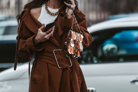 Milan, Italy - February, 24: Street style, woman wearing a brown oversized coat, black leather pants and neon orange shoes.のeditorial素材