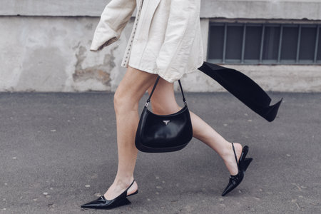 Milan, Italy - February, 24: Street style, woman wearing cream leather jacket, mini skirt with long train, black Prada bag and Prada heels.のeditorial素材