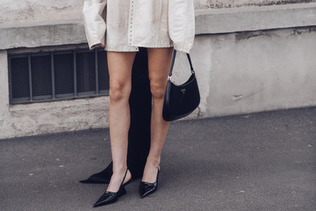 Milan, Italy - February, 24: Street style, woman wearing cream leather jacket, mini skirt with long train, black Prada bag and Prada heels.のeditorial素材