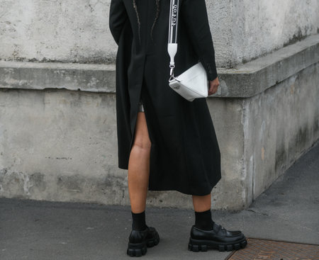 Milan, Italy - February, 24: Street style, woman wearing wearing yellow and grey shirt with matching shorts, black Prada tie, black coat, white Prada bag.のeditorial素材