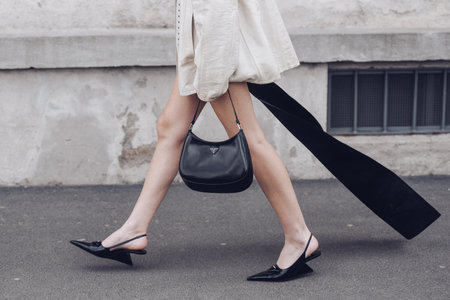 Milan, Italy - February, 24: Street style, woman wearing cream leather jacket, mini skirt with long train, black Prada bag and Prada heels.のeditorial素材