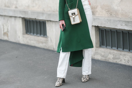 Milan, Italy - February, 24: Street style, woman wearing yellow shiny satin transparent dress, a black long coat, a black grained leather handbag and black ankle boots.のeditorial素材